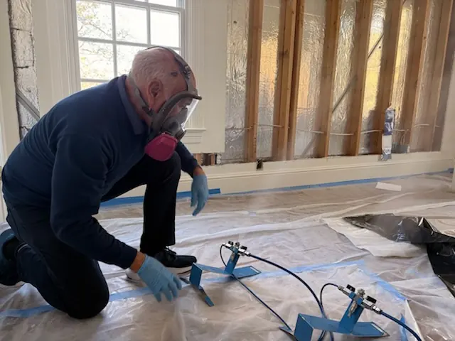 A restoration technician setting drying equipment in a Boston home stripped to the studs